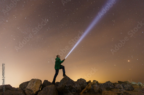 Silhouette of man with flashlight, wide stars and visible Milky way galaxy photo