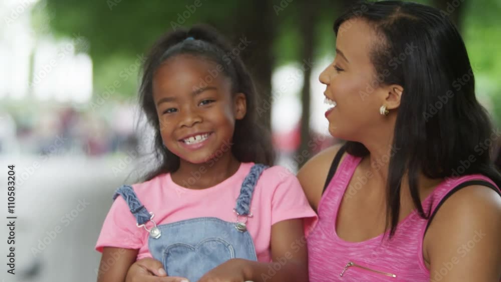 Portrait of smiling African American mother & daughter, relaxing in the park & looking at computer tablet. Portrait of smiling African American mother & daughter, relaxing in the park & looking at computer tablet.