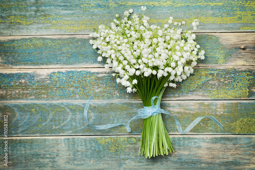 Fototapeta Naklejka Na Ścianę i Meble -  Beautiful bouquet of flowers lily of the valley on vintage wooden table from above, rustic background