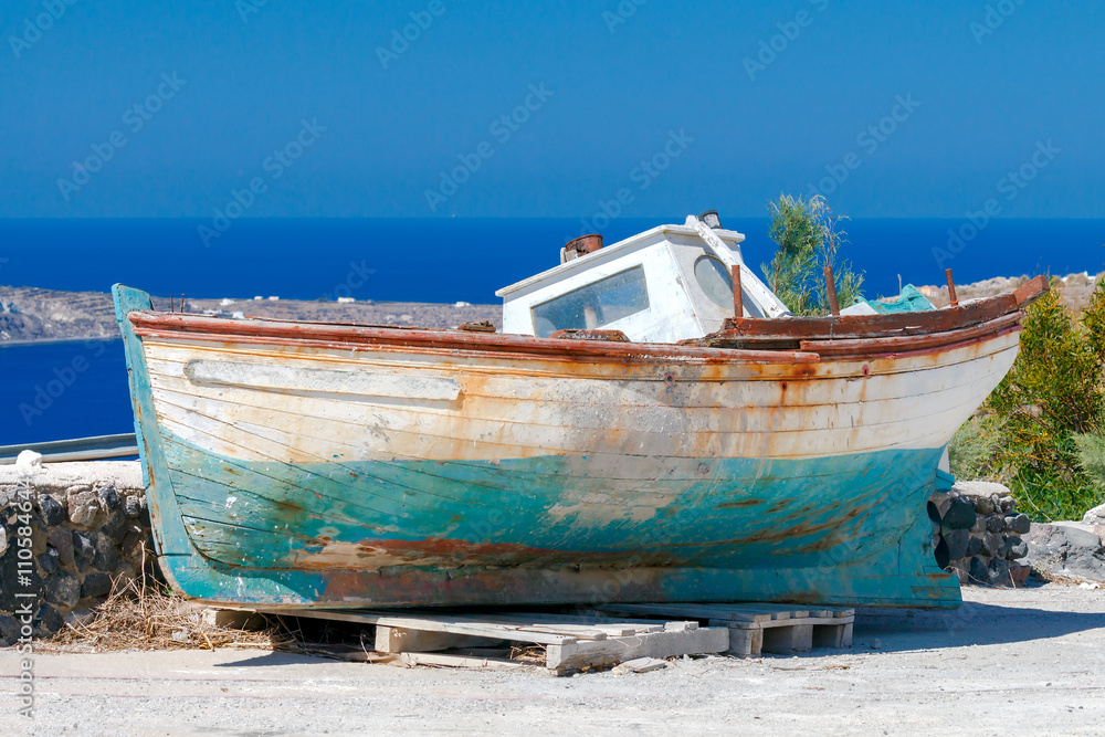 Oia. Old boat on the beach. - obrazy, fototapety, plakaty 