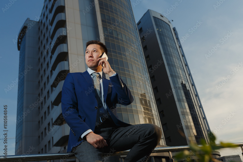 Korean businessman talking on phone in business district Korean businessman talking on phone in business district