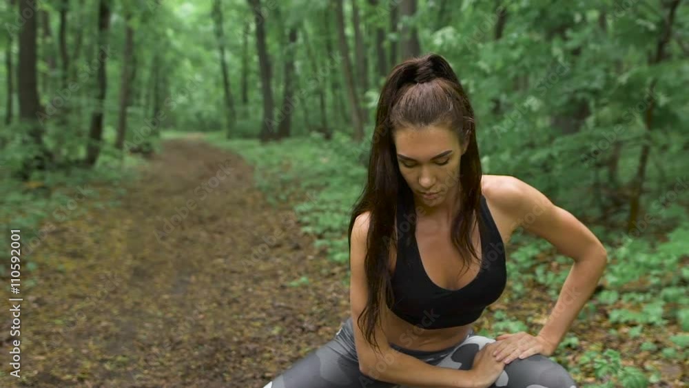 Slim fitness woman on a forest path. The brunette with long hair and performs an exercise in stretching. Slim fitness woman on a forest path. The brunette with long hair and performs an exercise in stretching.