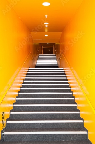 Long gray stairs with many steps in a high building with yellow wall