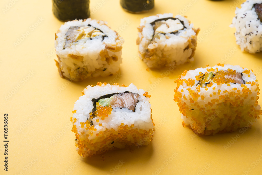 Various kinds of sushi food served on yellow blackground Various kinds of sushi food served on yellow blackground