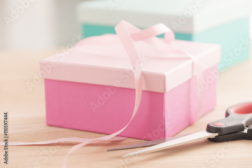 Gift wrapping for a holiday celebration, birthday or surprise party. Preparation of present with ribbon, box and decoration on table. Festive package material. © larshallstrom