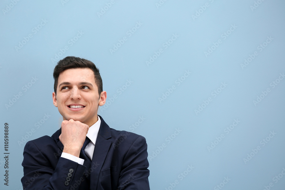 Attractive young man in a suit against light blue wall Attractive young man in a suit against light blue wall