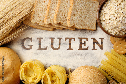 The word GLUTEN and flour products on wooden surface closeup