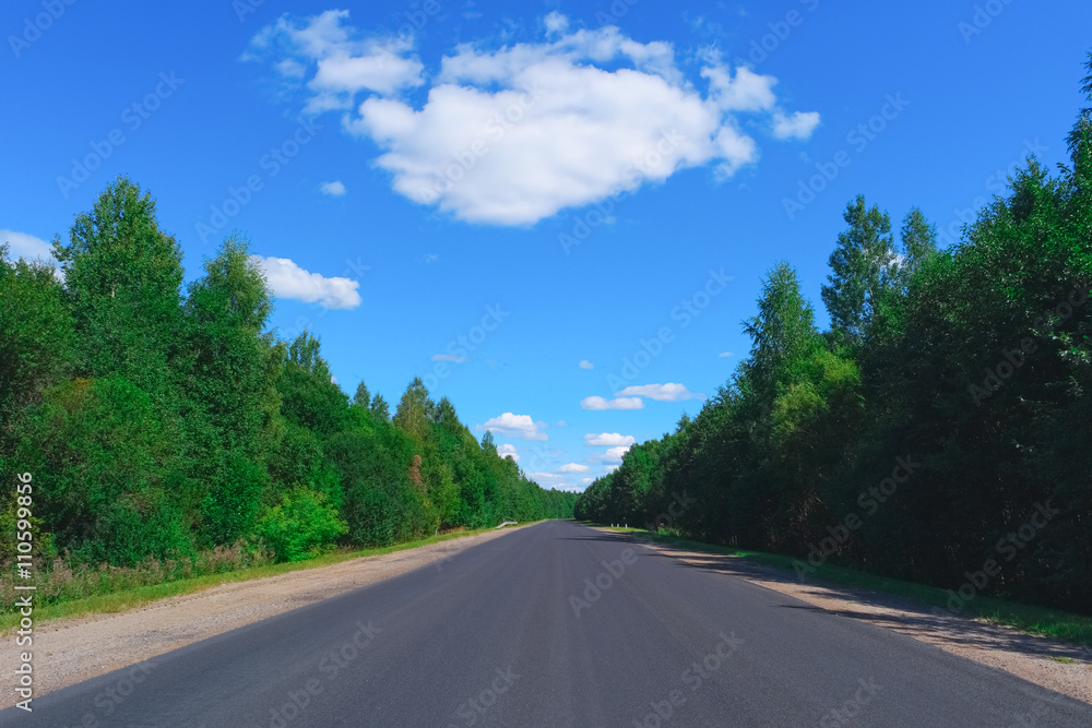 Obraz premium Empty highway, green forest and clouds