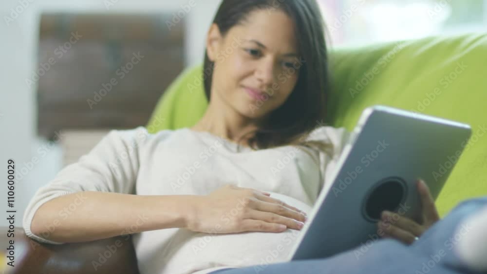 Affectionate pregnant couple relaxing at home with tablet computer Affectionate pregnant couple relaxing at home with tablet computer