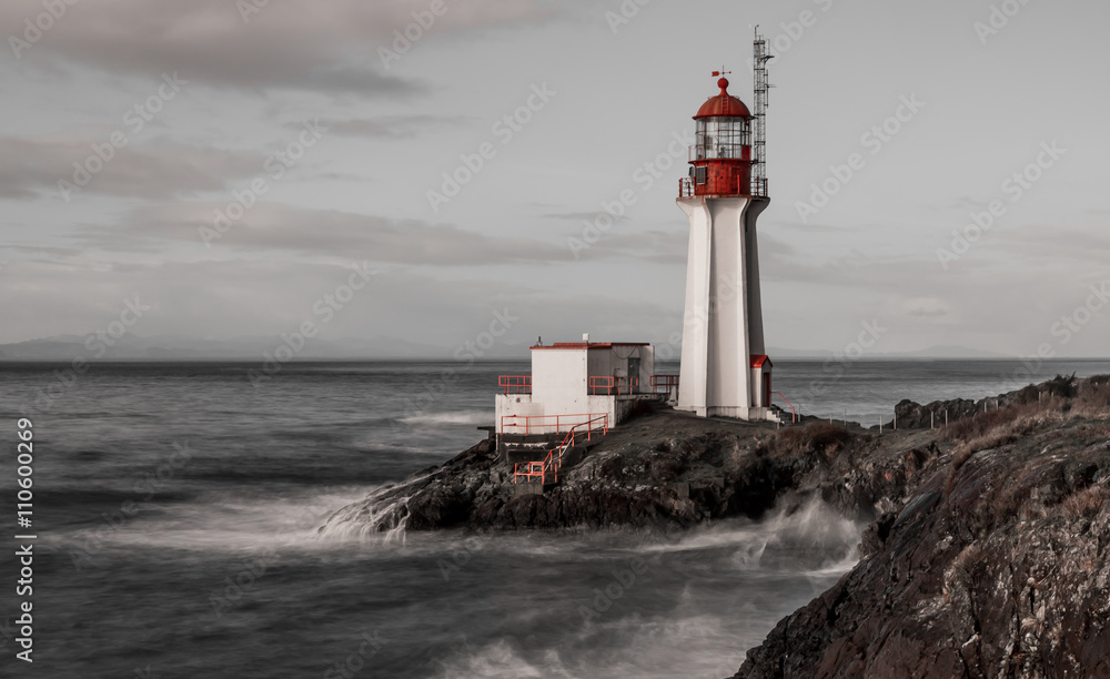 Black and white long exposure with contrasting red features of Shearingham lighthouse on Vancouver Island British Columbia, Canada.