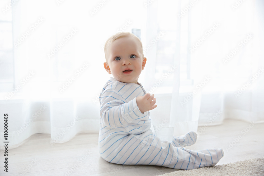Adorable baby boy sitting on the floor, close up Adorable baby boy sitting on the floor, close up