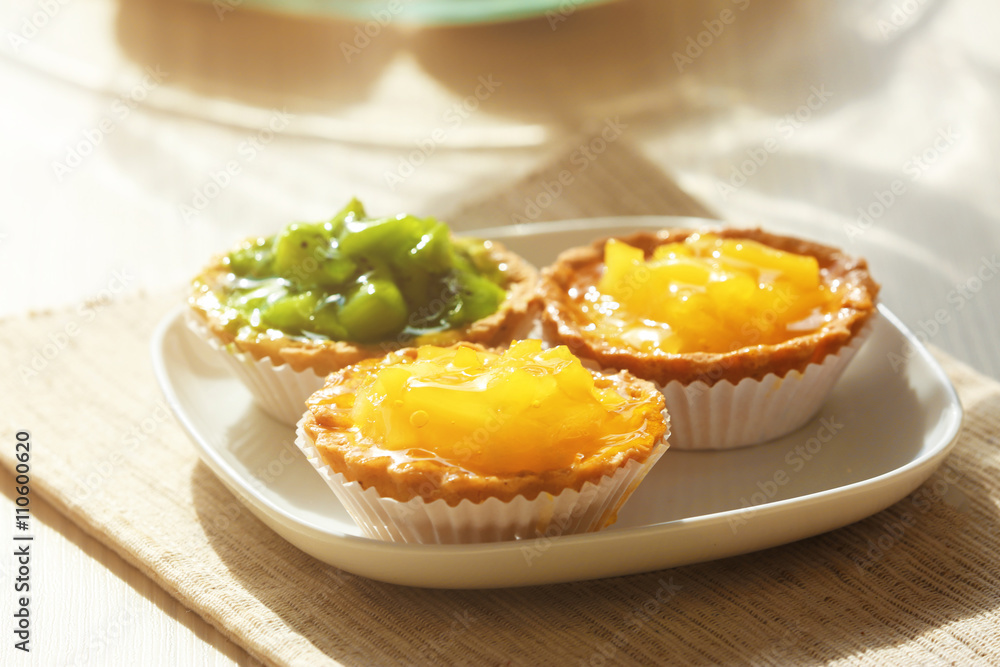 Fresh homemade fruit tarts with citruses and kiwi on a white table. Fresh homemade fruit tarts with citruses and kiwi on a white table.