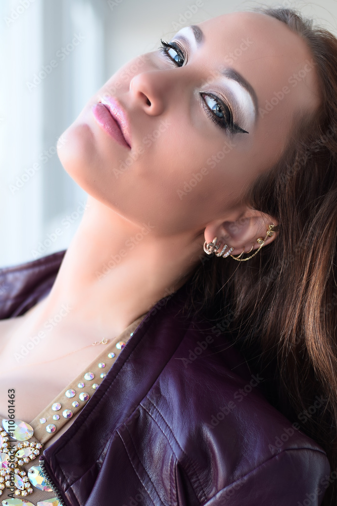 Glamorous young brunette woman in purple leather jacket and sparkly bra with beautiful makeup