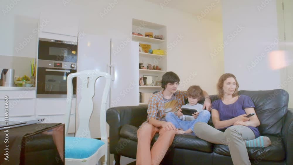 little boy playing portable game console. the family watching him with interest little boy playing portable game console. the family watching him with interest
