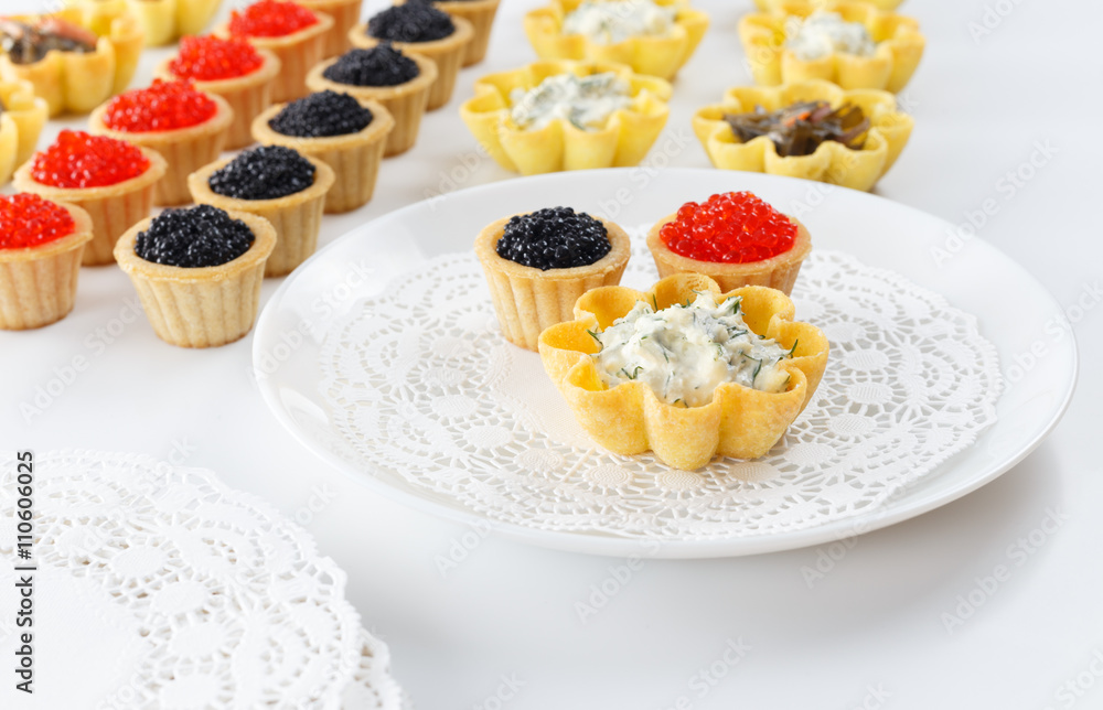 Tartlets filled with cheese and dill salad and caviar and plate with tartlets against white background Tartlets filled with cheese and dill salad and caviar and plate with tartlets against white background
