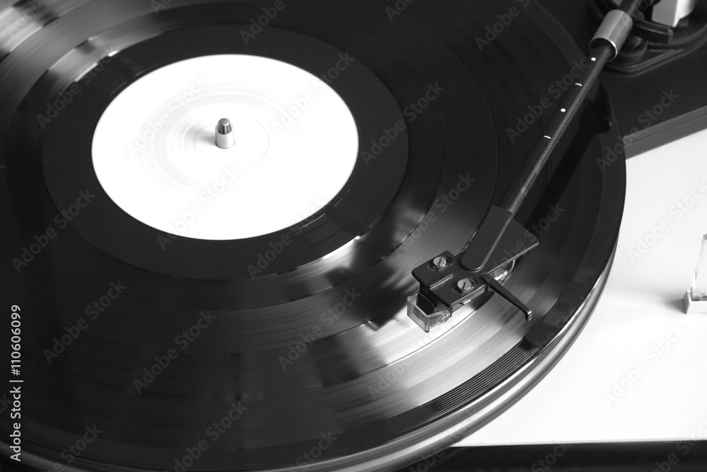 Fotografie Modern record player with magnetic stylus in silver case playing a vinyl record with white label