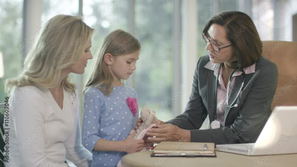 Friendly doctor talking to parent and child patient in office Friendly doctor talking to parent and child patient in office