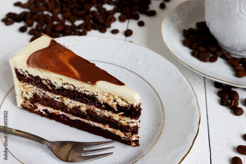 Kawałek ciasta czekoladowego z kremem na talerzyku, ziarna kawy