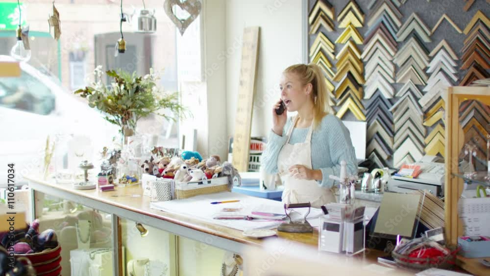 Cheerful business owner makes a phone call behind the counter of her shop Cheerful business owner makes a phone call behind the counter of her shop