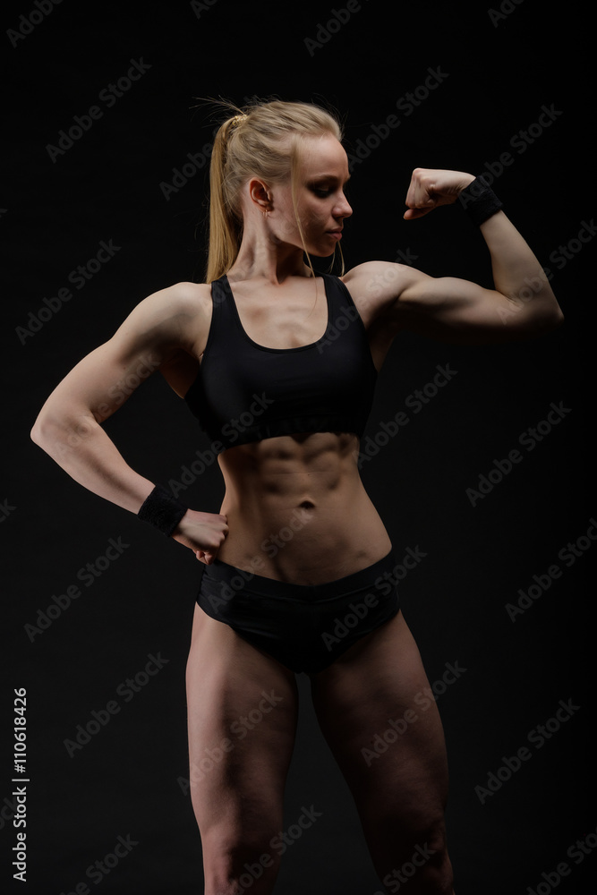 Fototapeta premium Young muscular woman posing on black