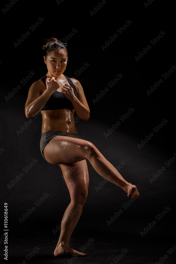 Young muscular woman posing on black