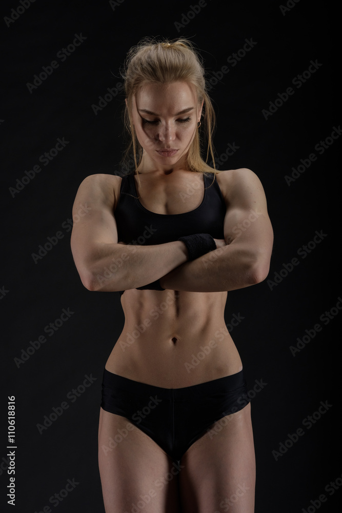 Fototapeta premium Young muscular woman posing on black