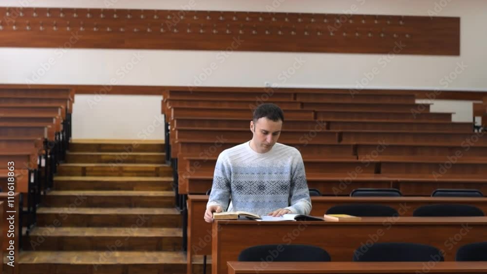 Student turns the pages of books at the desk in the reading room. He is looking for information in reference books. Student turns the pages of books at the desk in the reading room. He is looking for information in reference books.