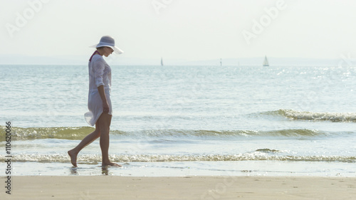 Fotografija Female walking along the shore of the beach alone