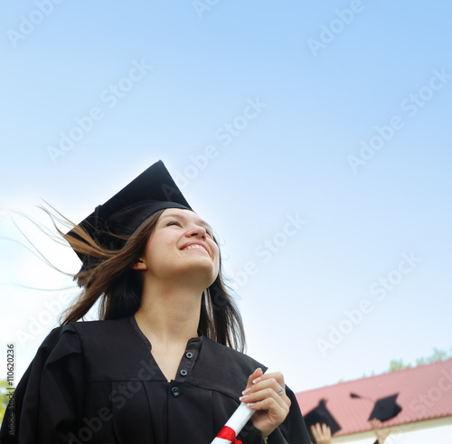 Girl in a cap and gown looking up.