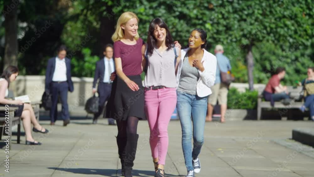 Happy attractive female friends chatting as they walk through city Happy attractive female friends chatting as they walk through city