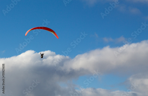 Hanglider - Paraglider high in the clouds over the ocean on a summer day