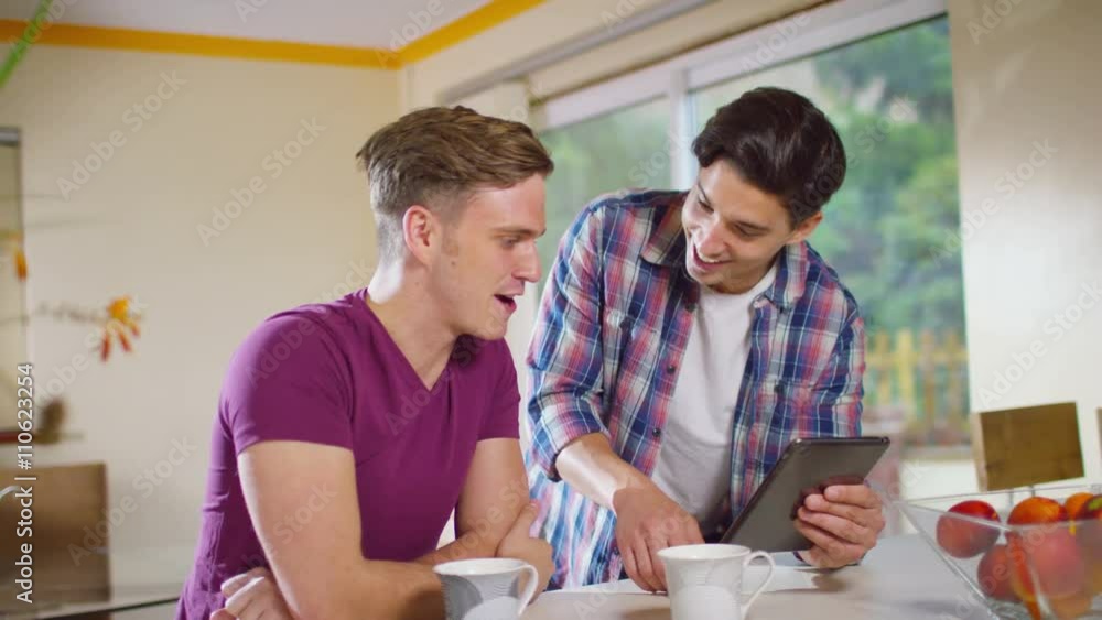 Young gay couple relaxing at home with computer tablet Young gay couple relaxing at home with computer tablet