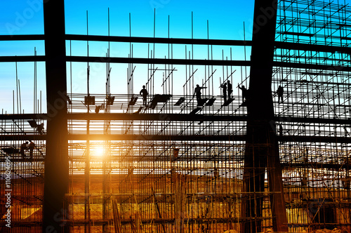 Fotografie Silhouette of construction workers on scaffolding