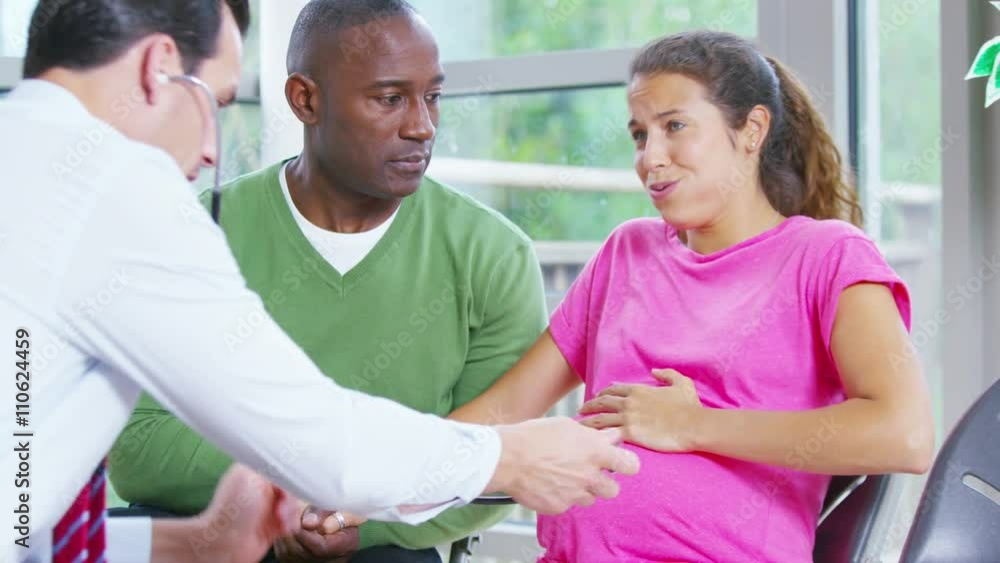 Pregnant woman going into labour is supported by her partner & medical staff Pregnant woman going into labour is supported by her partner & medical staff