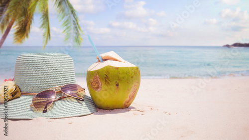 Summer vacation concept straw hat with sunglasses and coconut cocktail on sandy tropical beach