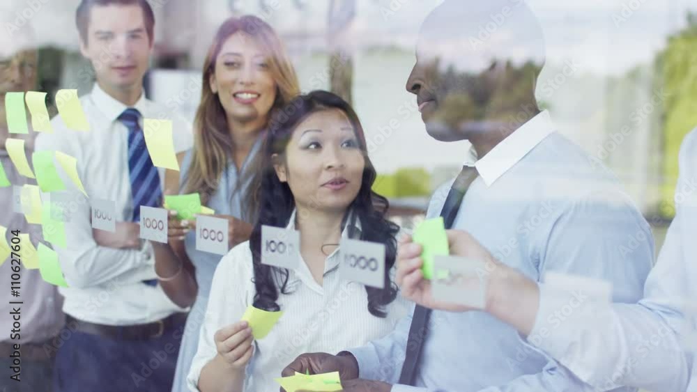 Mixed ethnicity business team brainstorming for ideas with sticky notes Mixed ethnicity business team brainstorming for ideas with sticky notes