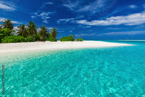 White sandy tropical beach with palm trees and blue lagoon