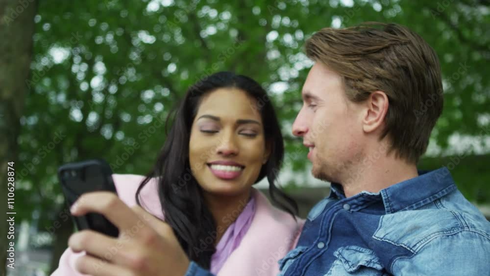 Romantic mixed ethnicity couple pose for a selfie in the park Romantic mixed ethnicity couple pose for a selfie in the park