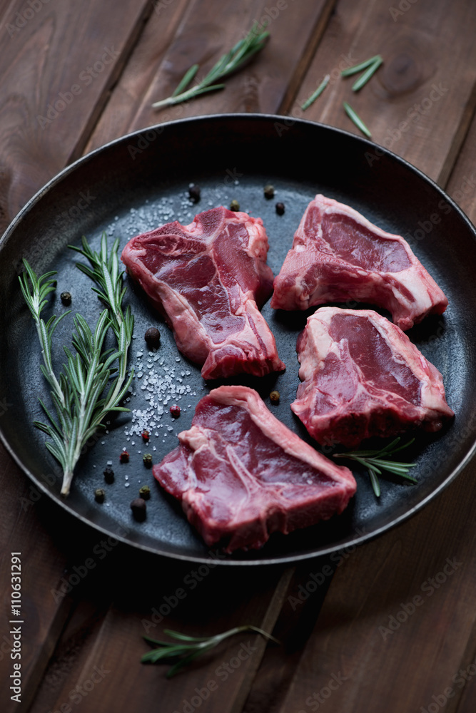 Close-up of a frying pan with raw seasoned T-bone lamb steaks Close-up of a frying pan with raw seasoned T-bone lamb steaks