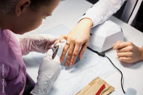 Manicure care procedure, Close-up photo Of Beautician Hand Painting Nails Of Woman In Salon © cherry_d