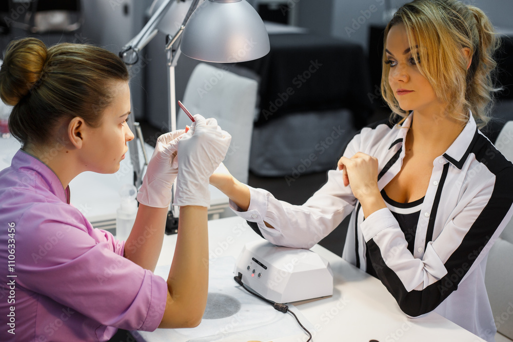 Fototapeta premium Manicure care procedure, Close-up photo Of Beautician Hand Painting Nails Of Woman In Salon