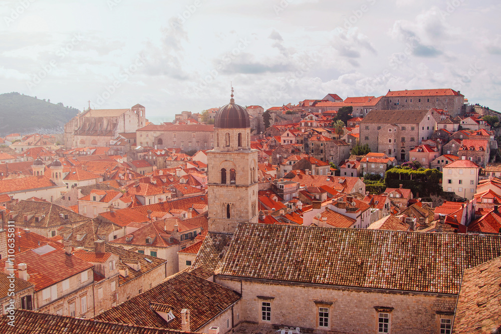 Sunrise over the old city of Dubrovnik, Croatia, Franciscan church with tower bell and roofs of old houses, warm filter applied