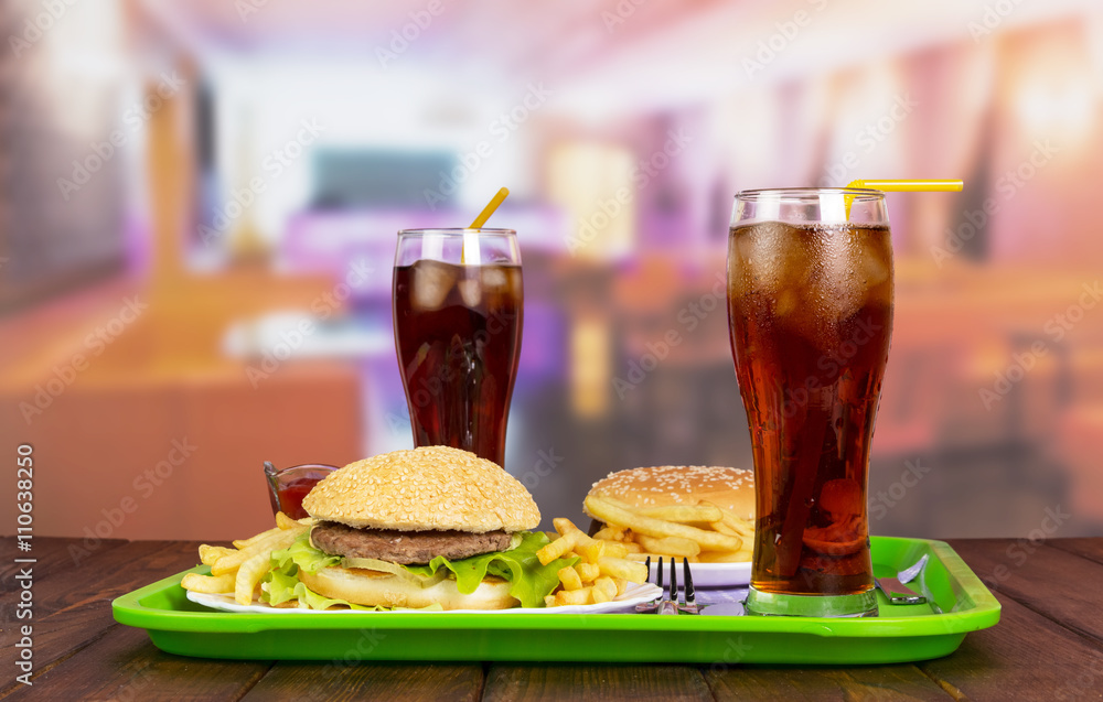 Hamburgers, french fries with sauce, cola on green spacing Hamburgers, french fries with sauce, cola on green spacing