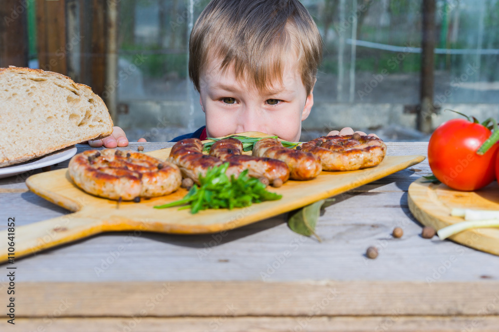 Boy looking on BBQ on the table. Focus on child.