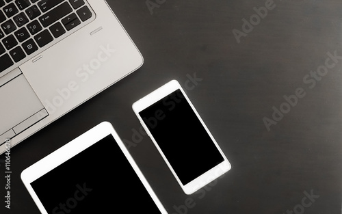 Digital tablet,smart phone and laptop on the black wooden desk