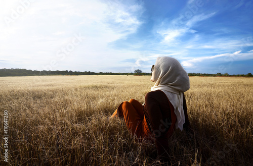 Muslim woman wearing hijab relaxing on savanna photo