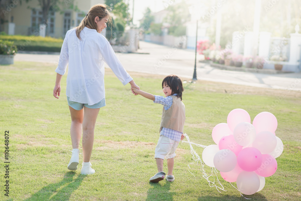 Asian mother and son holding hand together and walking