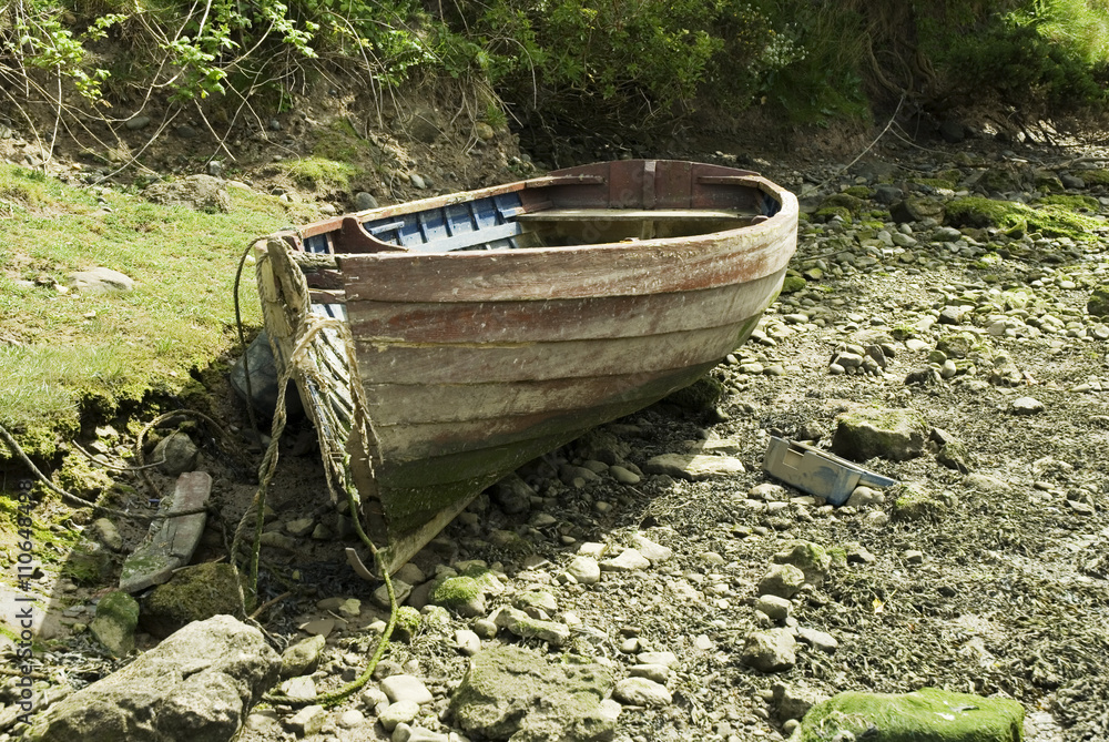 old rowing boat sitting abandoned on a pebble beach old rowing boat sitting abandoned on a pebble beach