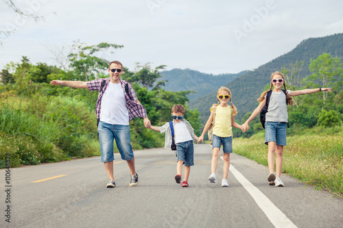 Father and children walking on the road at the day time.