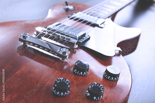 Brown electric guitar on black wooden background, close up photo